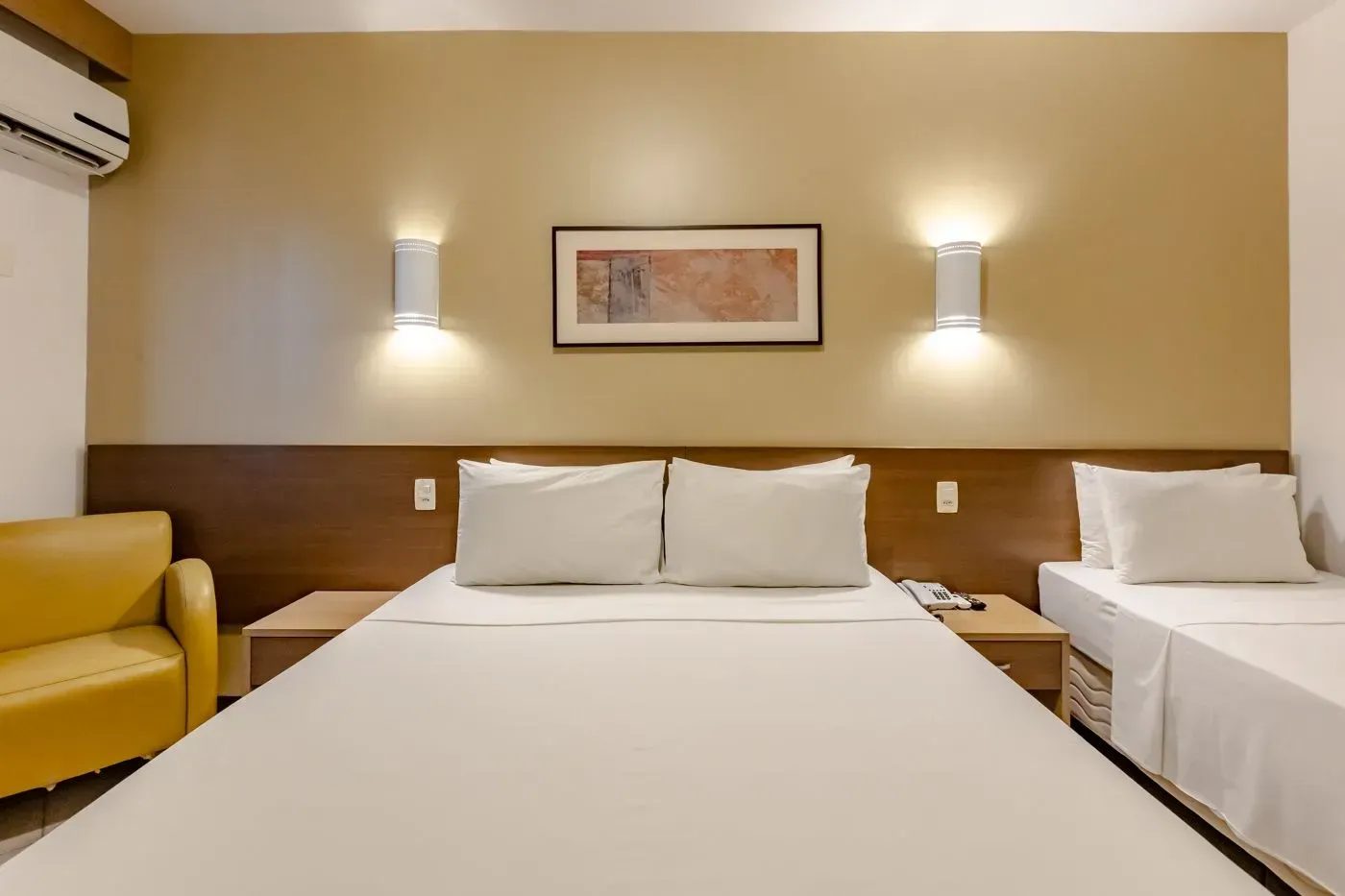 Um quarto de hotel com uma cama king size e uma cama de solteiro.