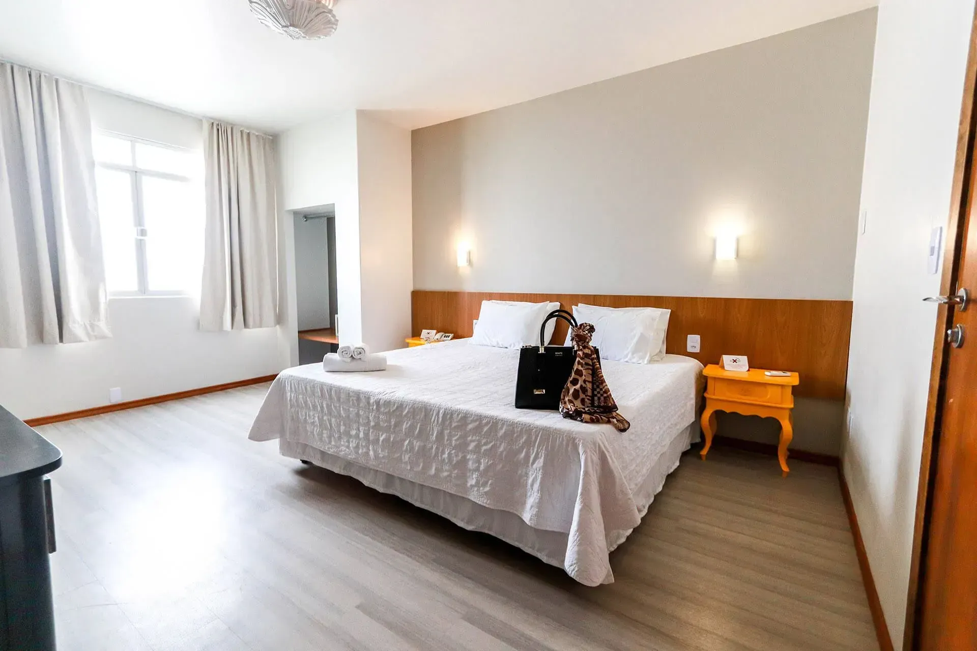 Um quarto de hotel com uma cama king size e duas mesas de cabeceira.
