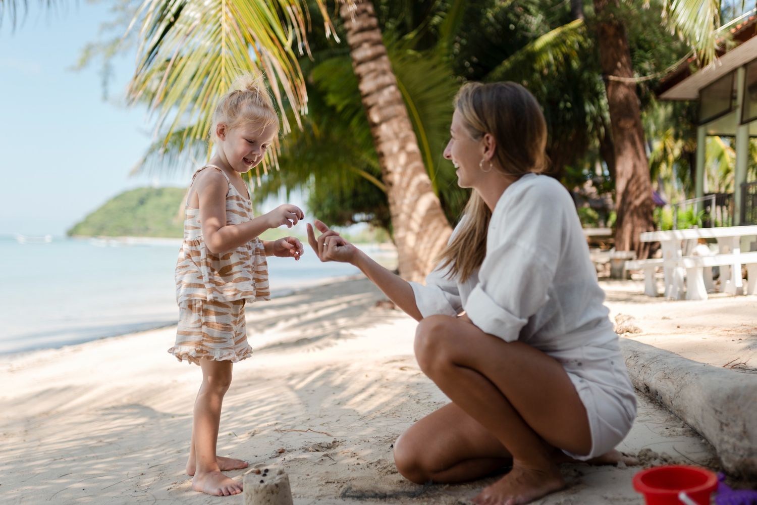 A mother on the beach showing her daughter something.