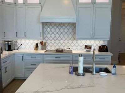A kitchen with white cabinets , a sink , and a stove top oven.