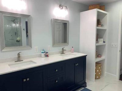 A bathroom with two sinks , two mirrors and a shelf.