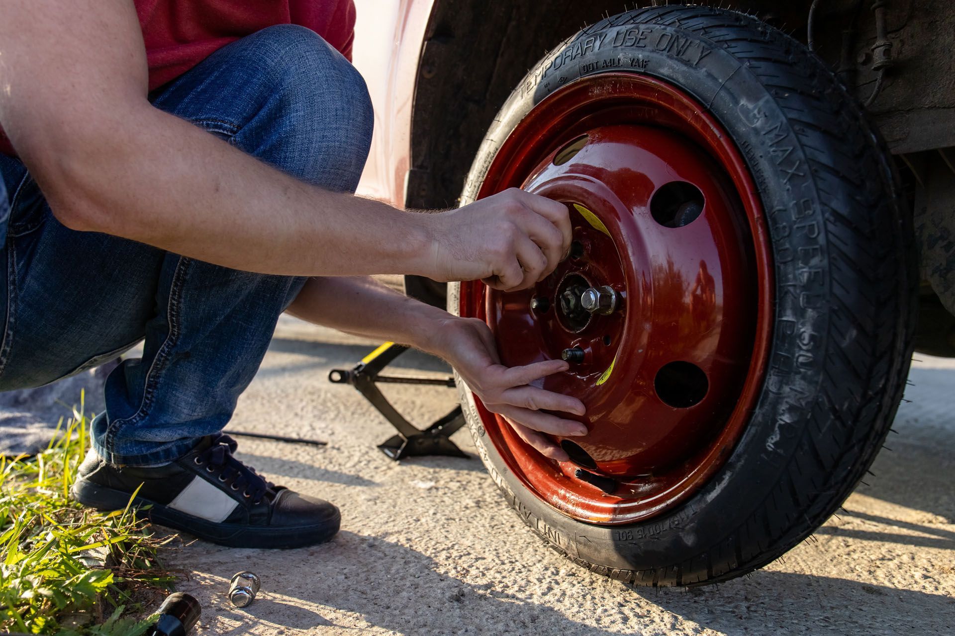 A man is changing a tire on a car with a jack.