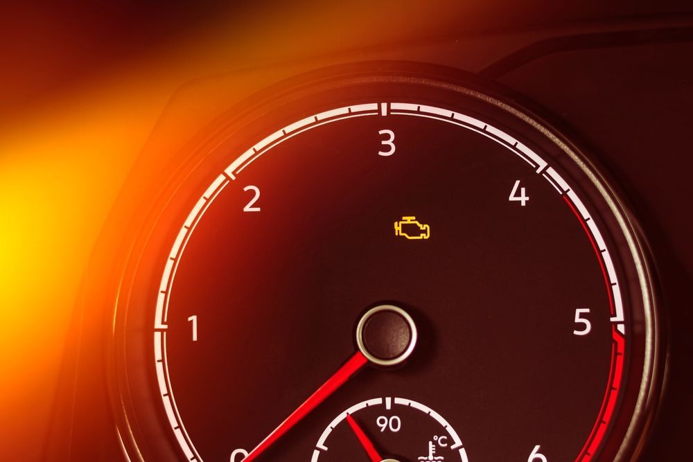 A close up of a car speedometer with a yellow light on it