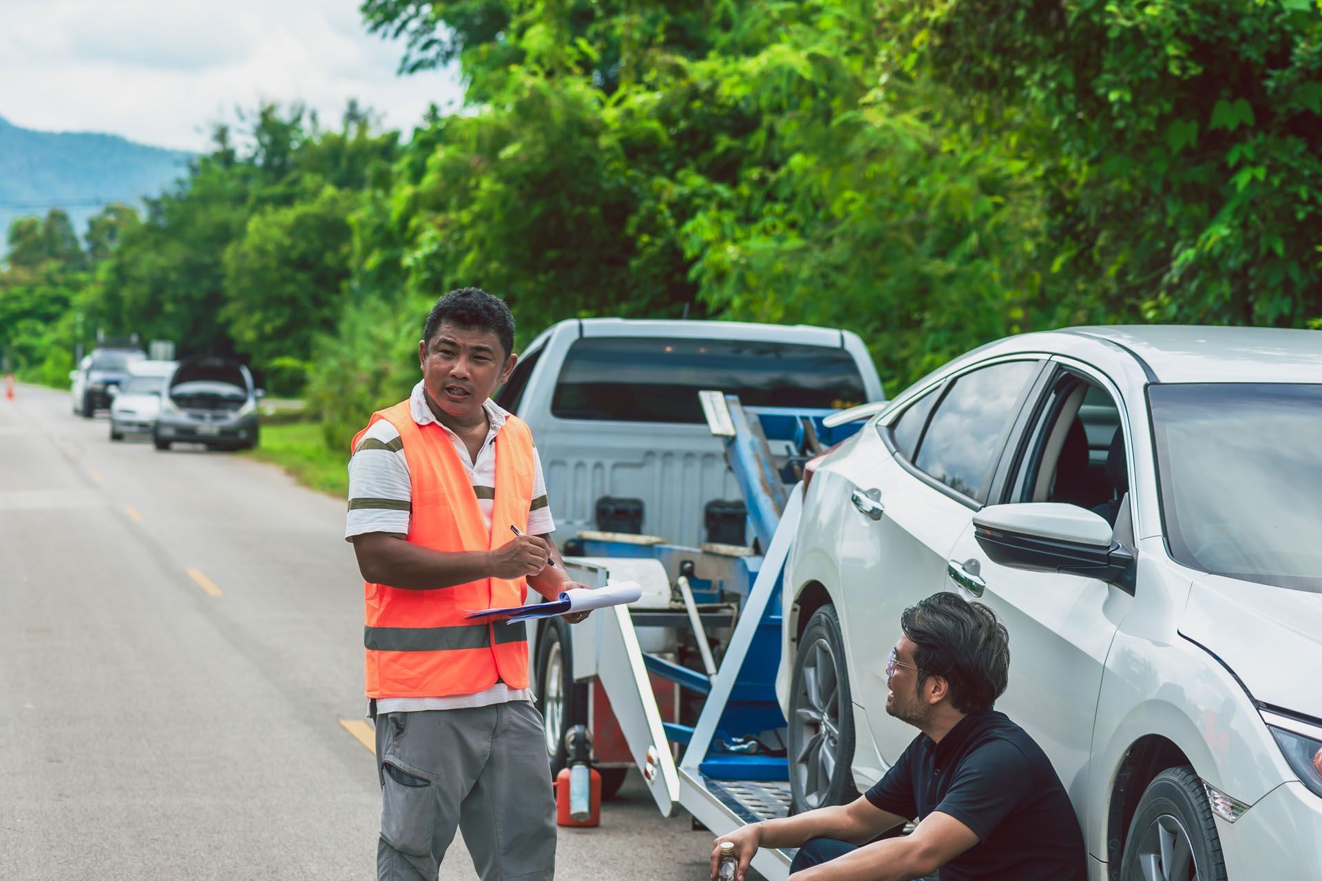 A tow truck is towing a car on the side of the road.