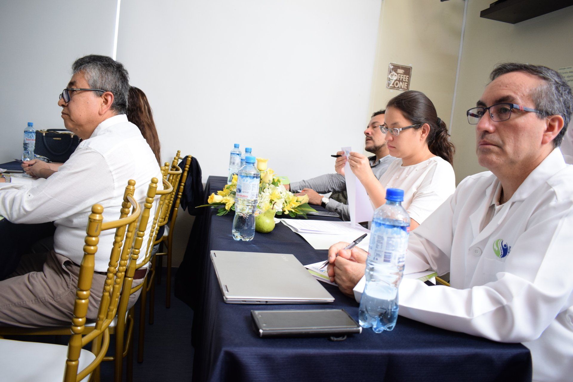 Un grupo de personas están sentadas en una mesa con botellas de agua.