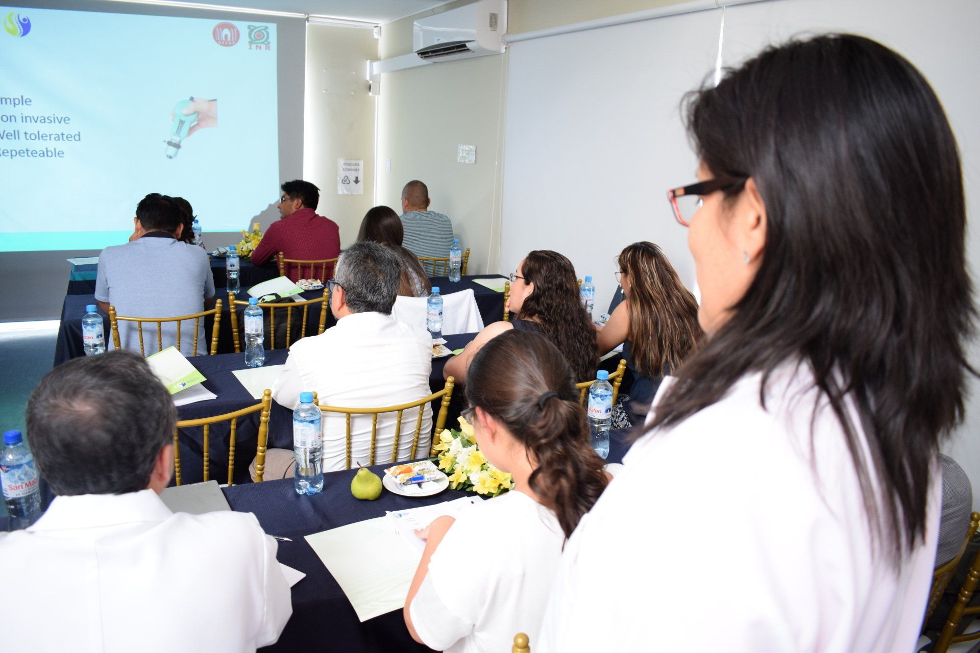 Una mujer está parada frente a un grupo de personas sentadas en mesas.