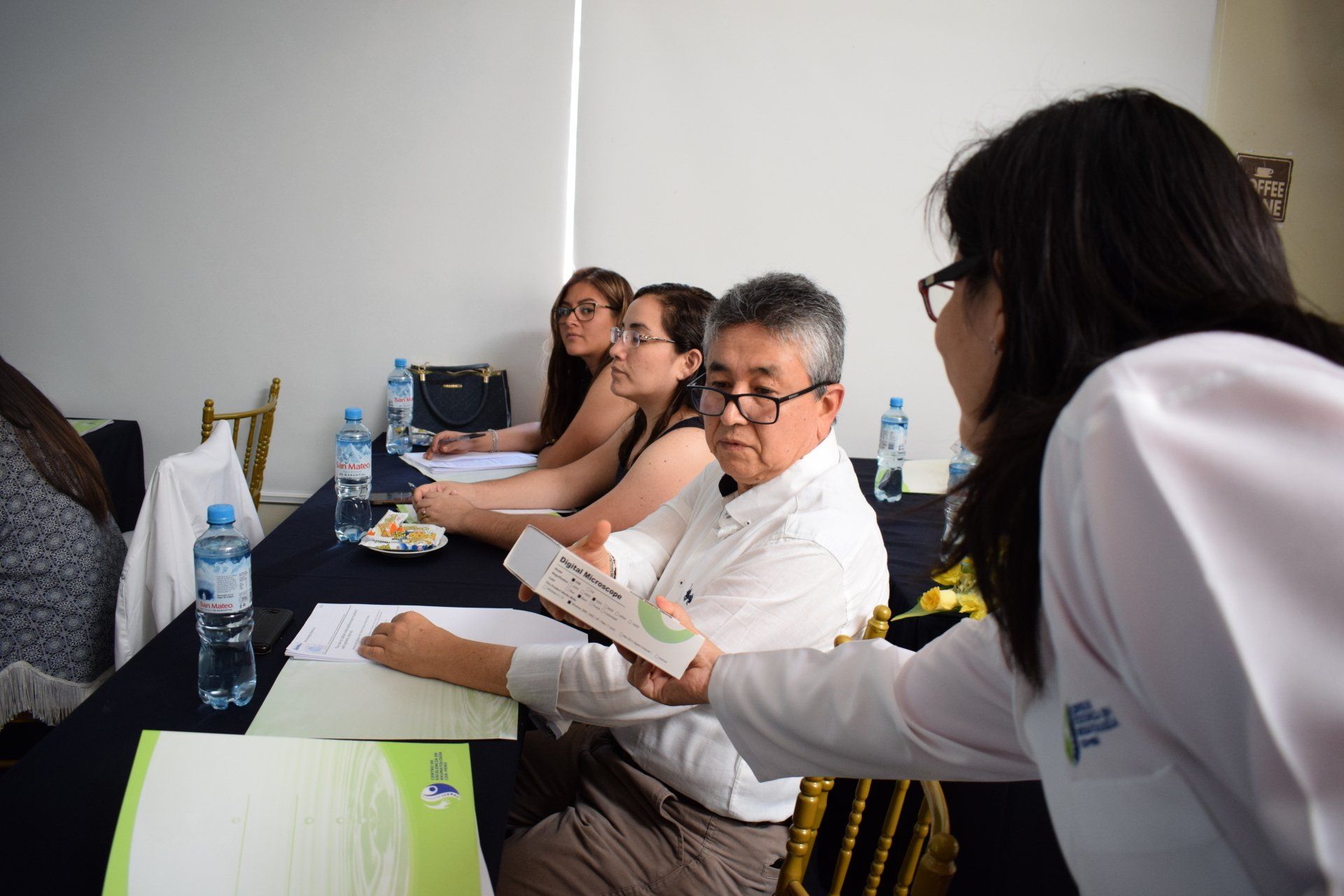 Un grupo de personas están sentadas en una mesa hablando entre sí.