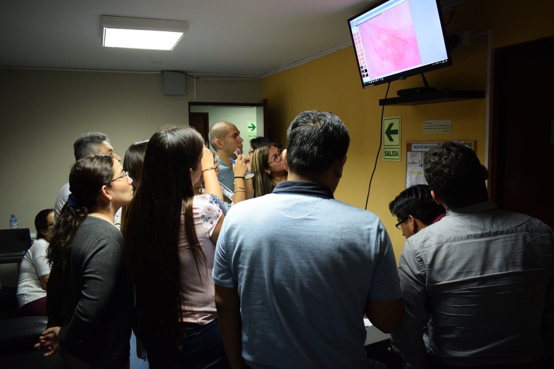 Un grupo de personas está mirando televisión en una habitación oscura.