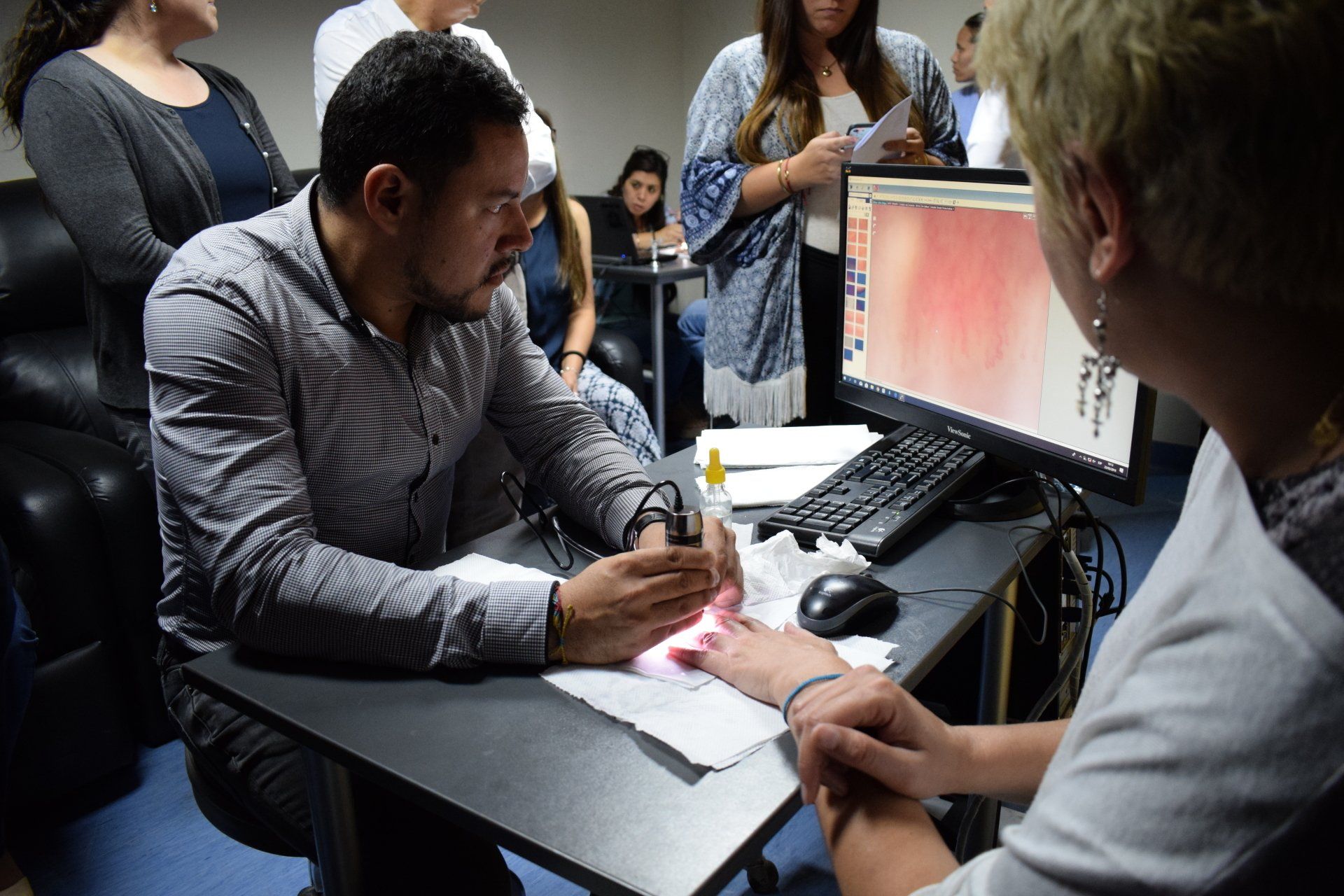 Un hombre está sentado en un escritorio mirando la mano de una mujer.