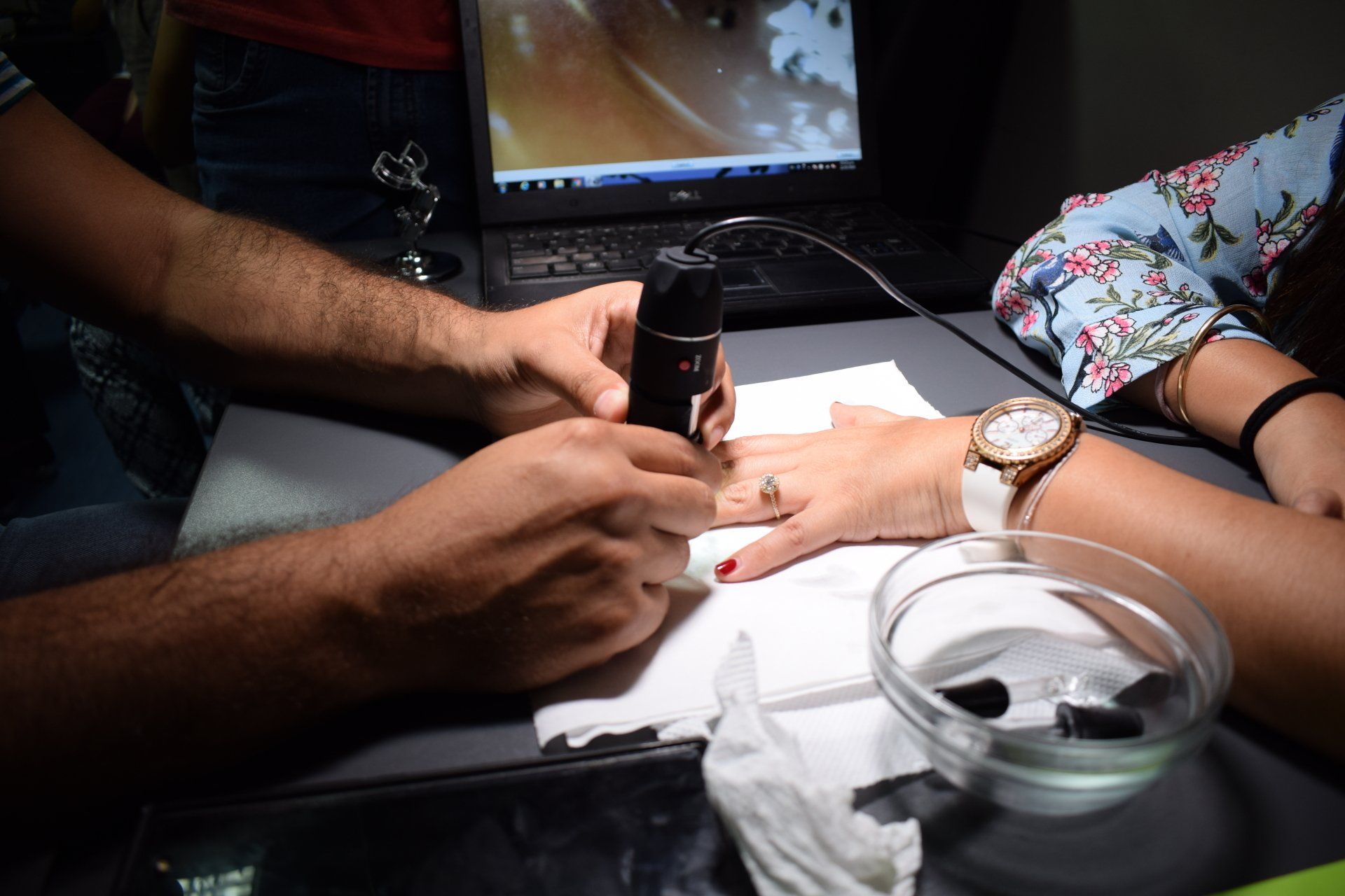 Un hombre está usando un microscopio para mirar la mano de una mujer.