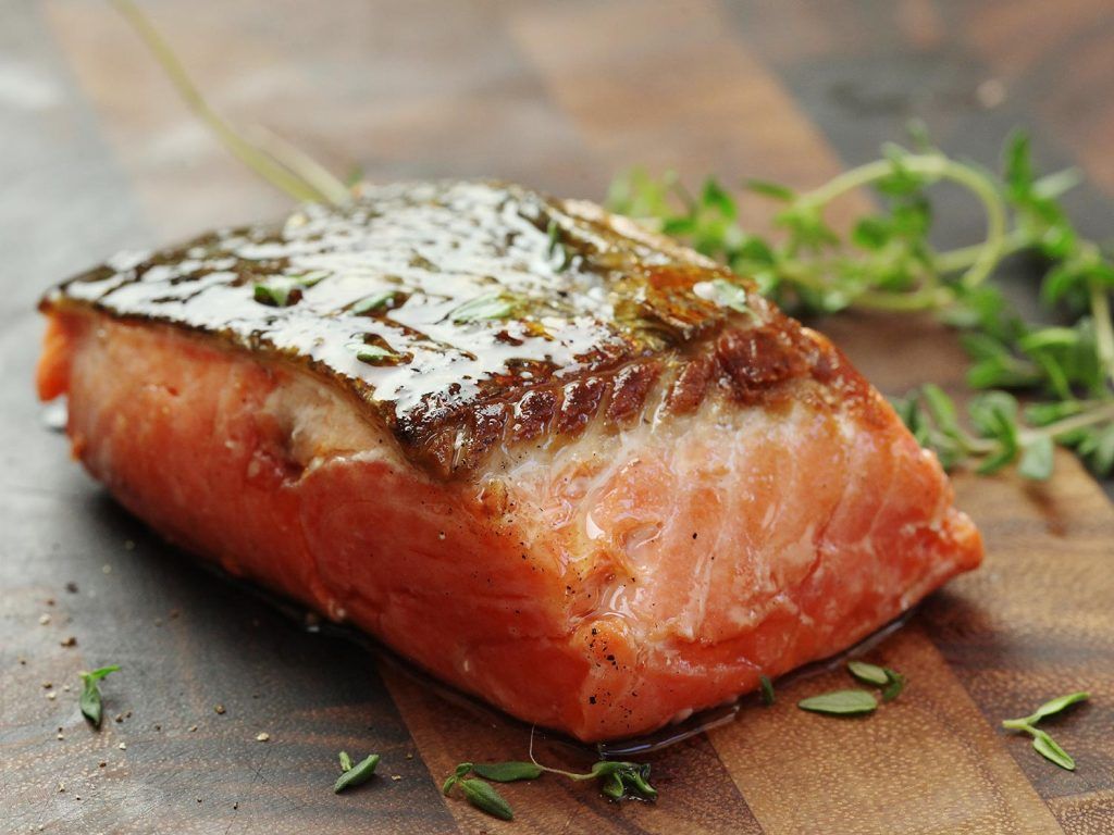 Un trozo de salmón reposa sobre una tabla de cortar de madera.