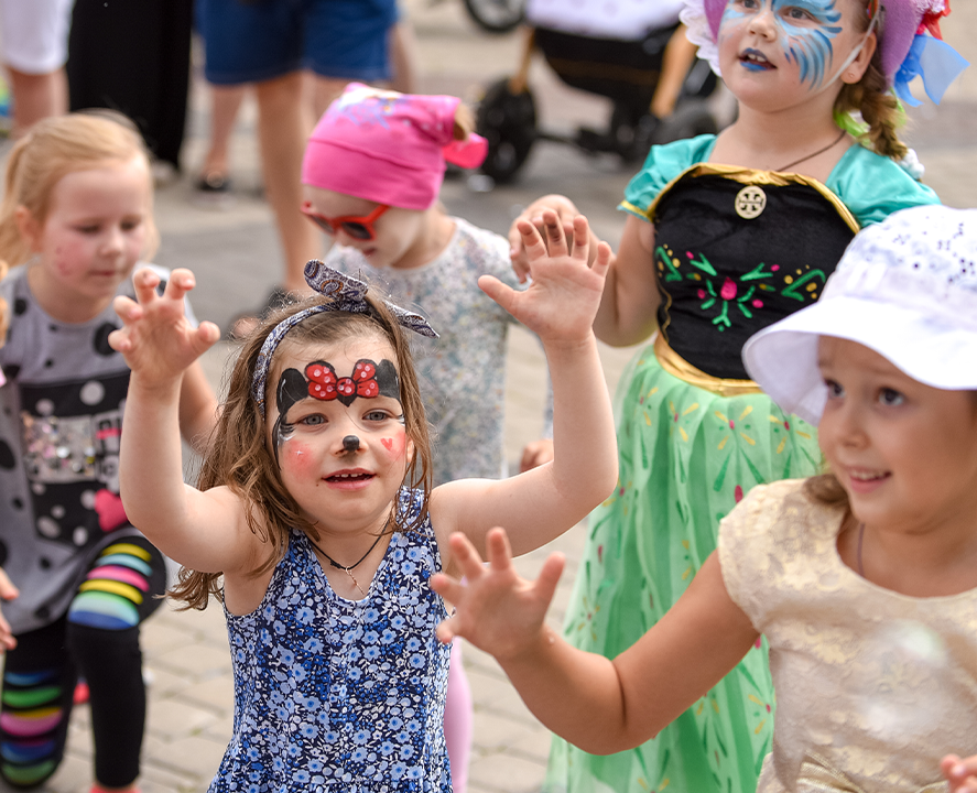 A group of children are dancing with a clown in a blue cape Pakenham