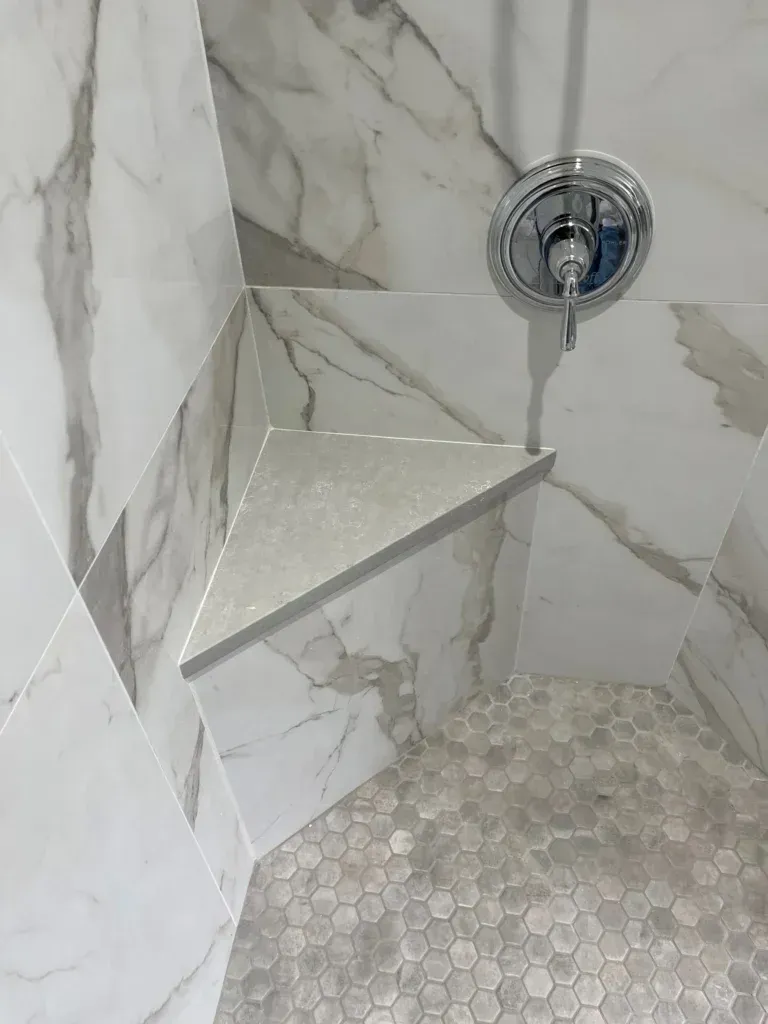 A shower with a corner shelf and a shower head.