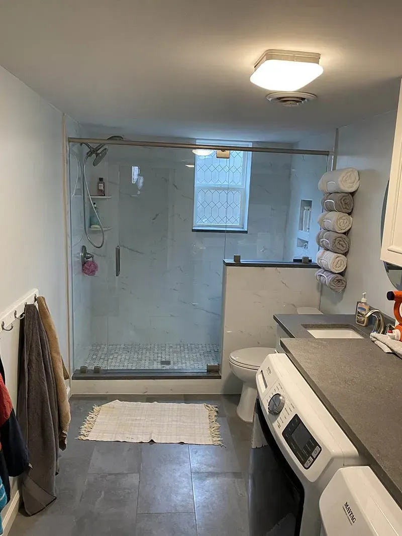 A bathroom with a washer and dryer , toilet , and shower.