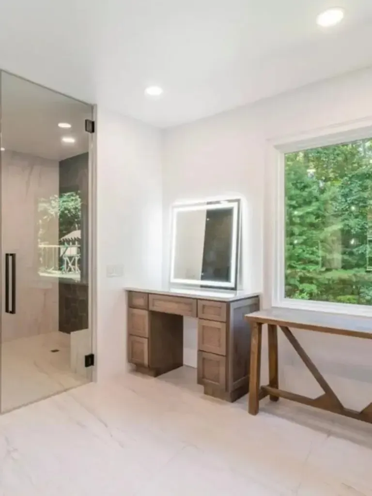 A bathroom with a vanity , mirror , and window.
