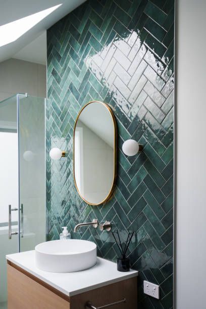 View of a nice, newly remodeled bathroom with green tiles and a mirror.