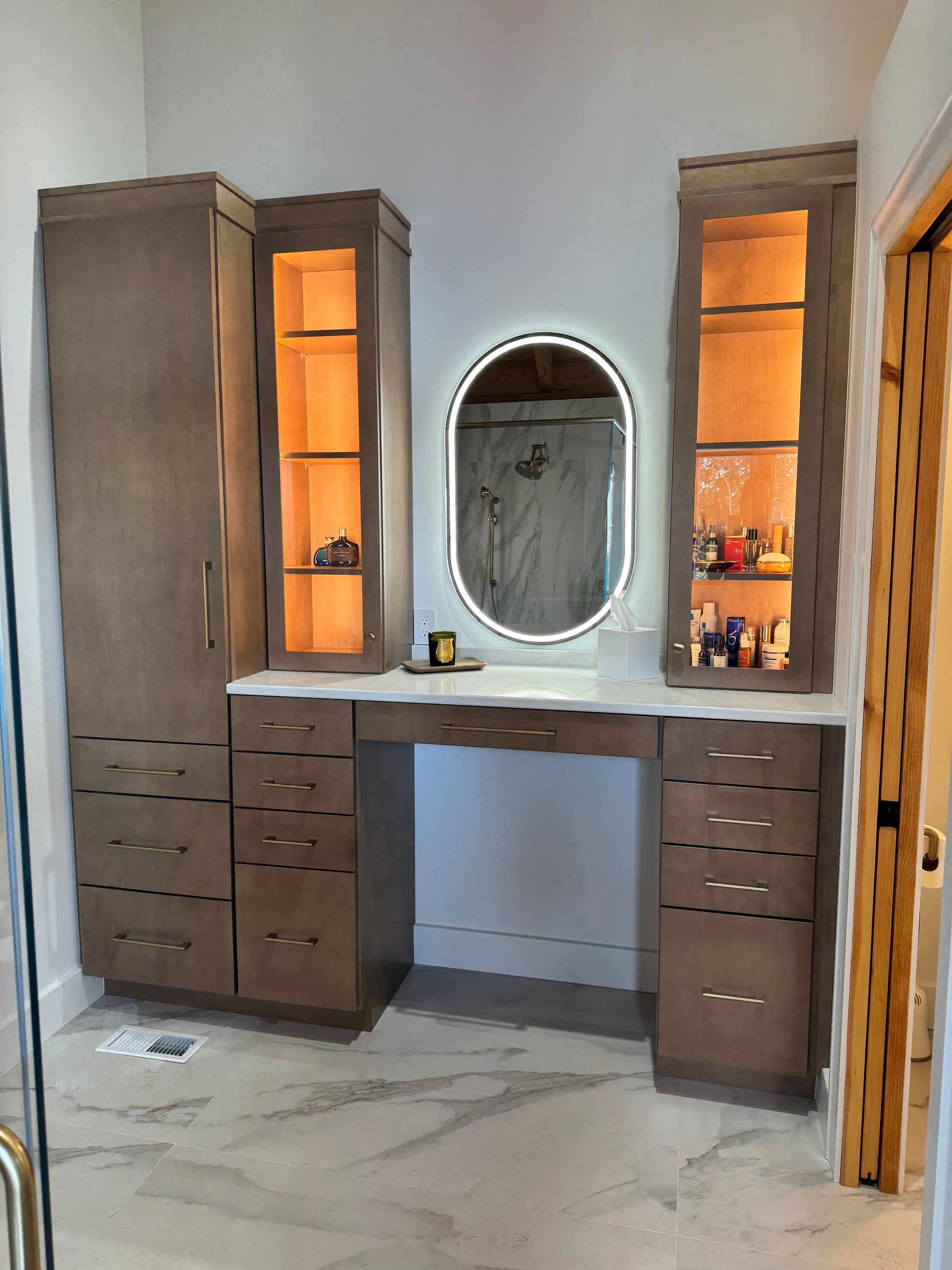 Bathroom vanity with built-in storage, drawers, and an oval mirror with LED lighting.