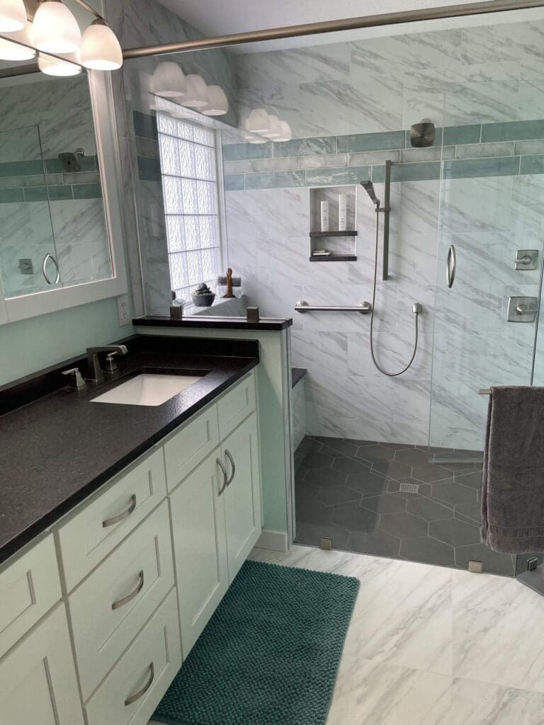 A bathroom with a sink , mirror , and walk in shower.