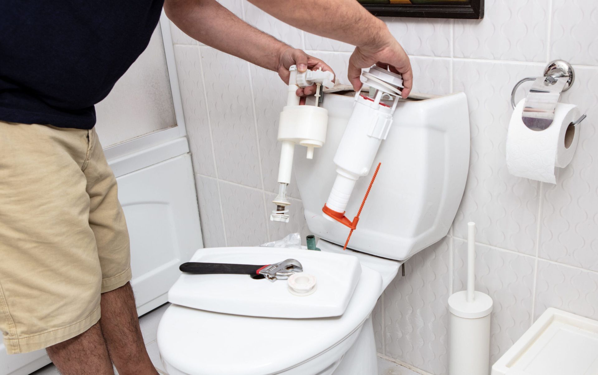 Man using tools repairing reservoir in a bathroom in a concept of DIY repairs with copy space