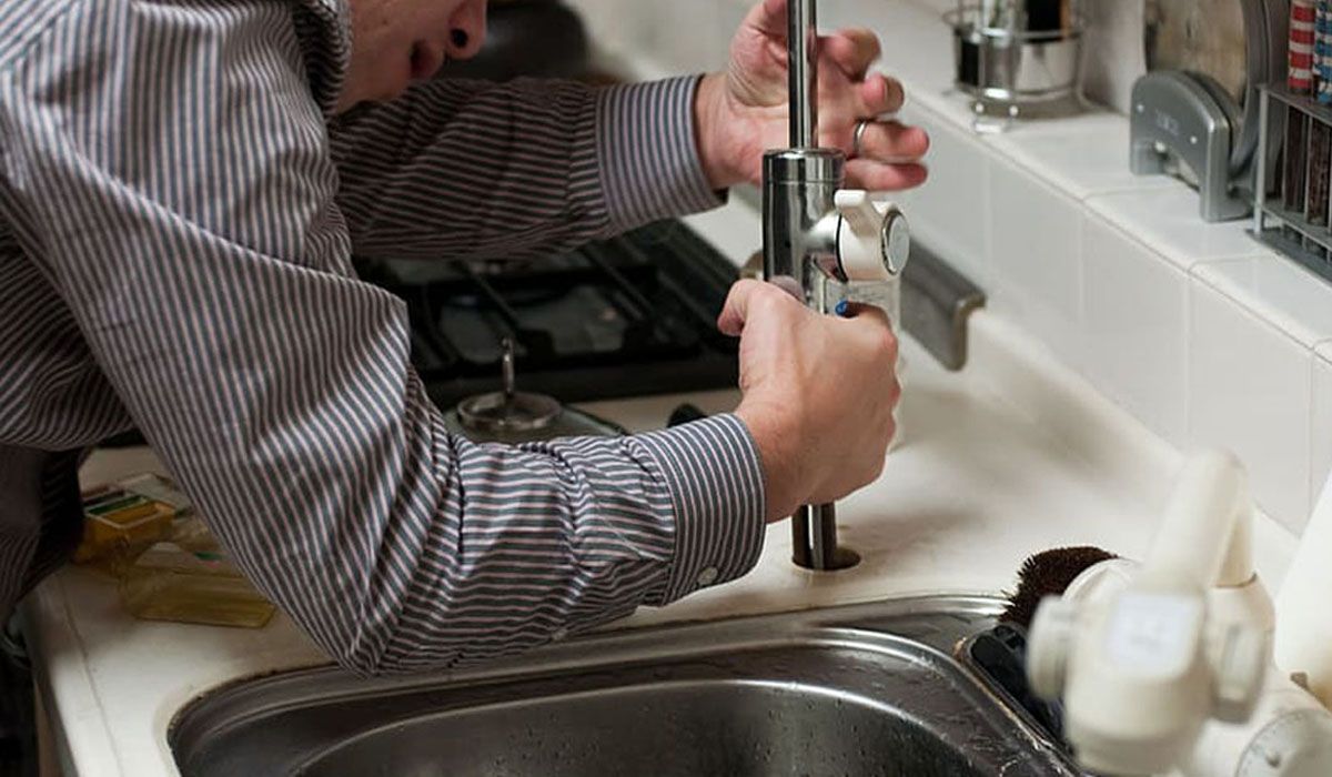 A man repairing the sink faucet.