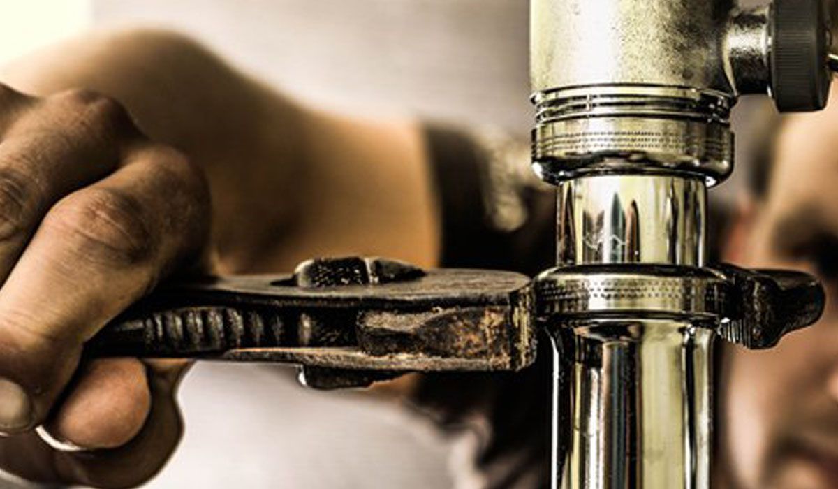 hands repairing a pipe with a wrench