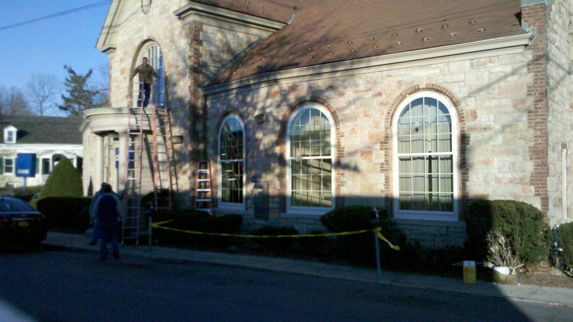 A brick building with arched windows is being painted