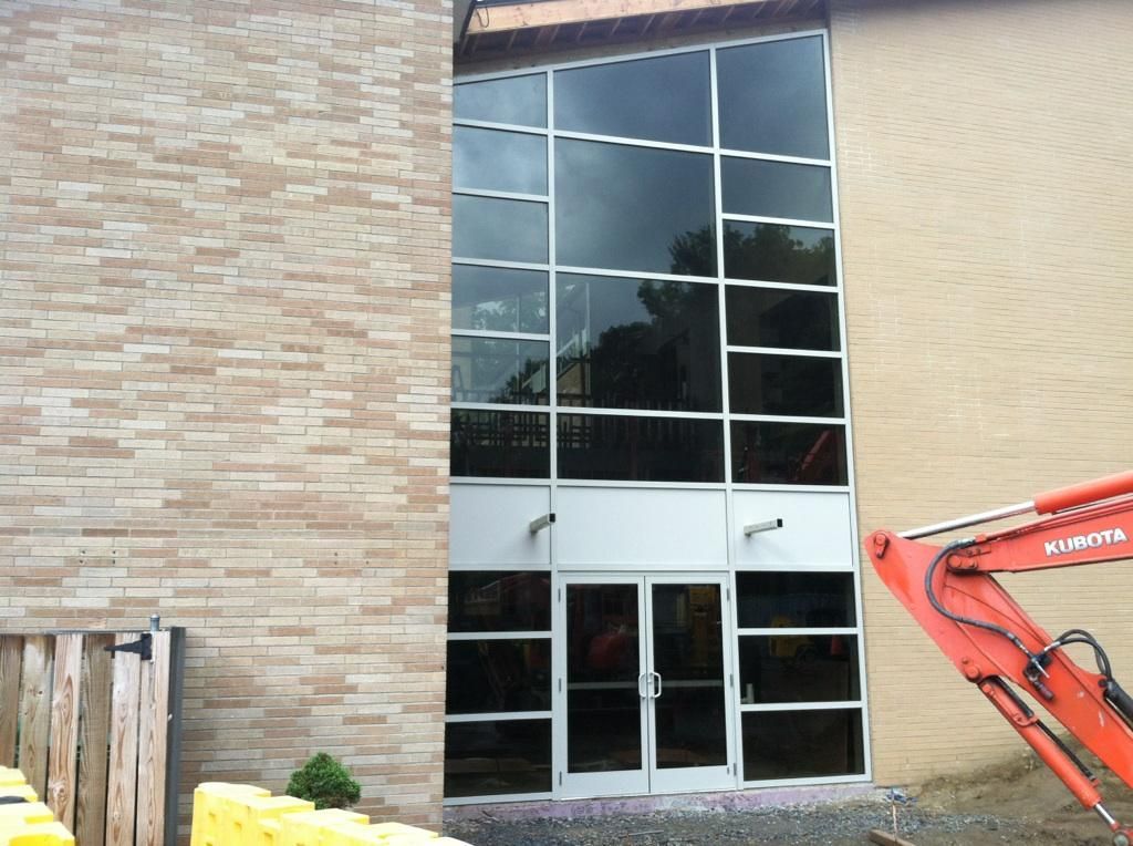 A large building with a lot of windows and an orange excavator in front of it