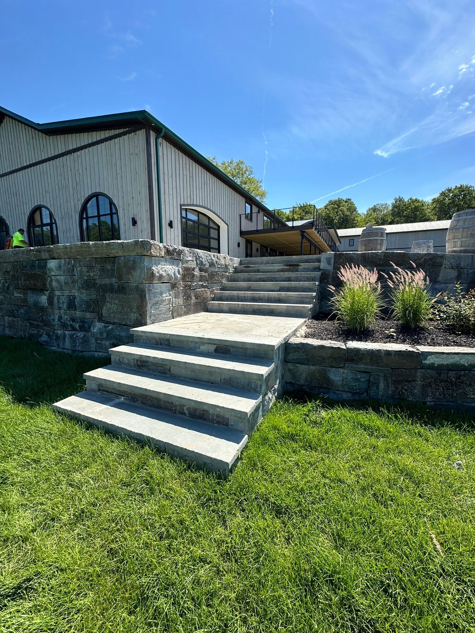 A house with stairs leading up to it is sitting on top of a lush green hillside.