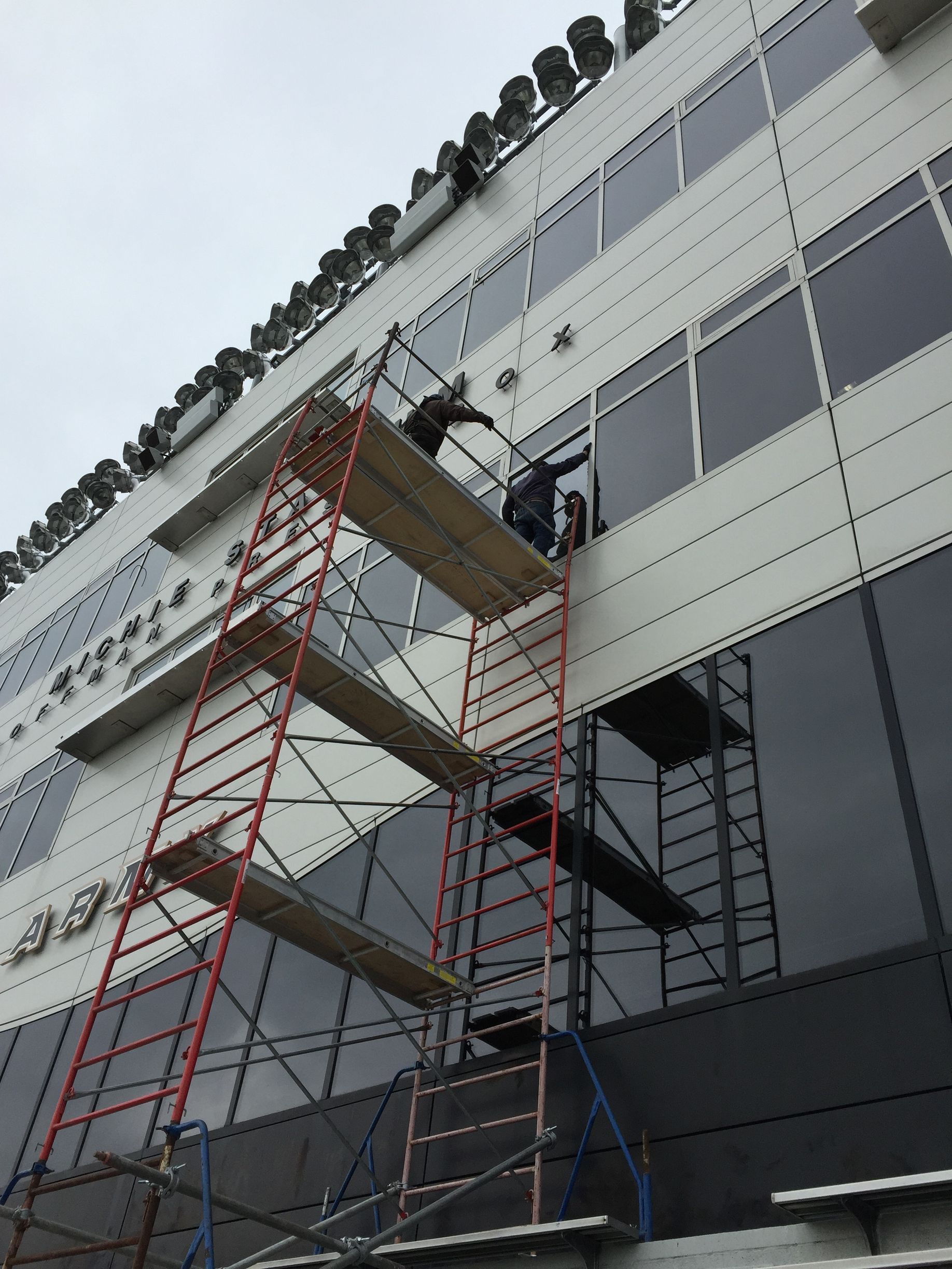 A man is standing on a scaffolding on the side of a building.