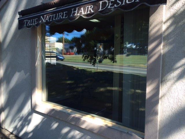 A window with an awning that says true nature hair design