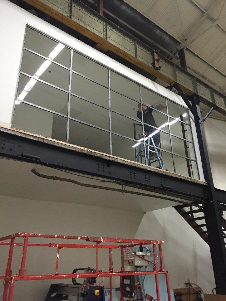 A man is standing on a ladder cleaning a window in a building.