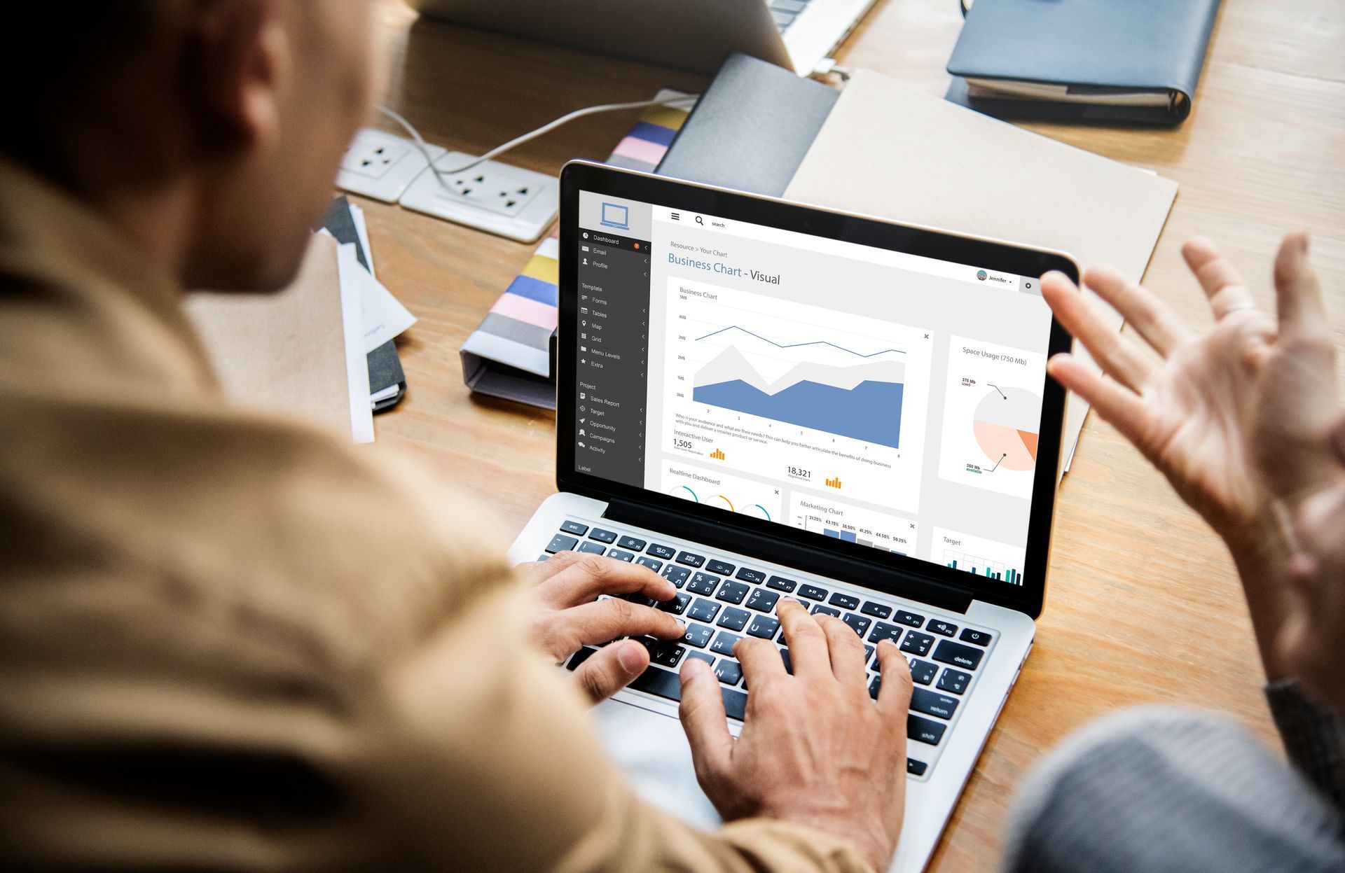 Two people looking at a laptop screen displaying graphs in an office setting.