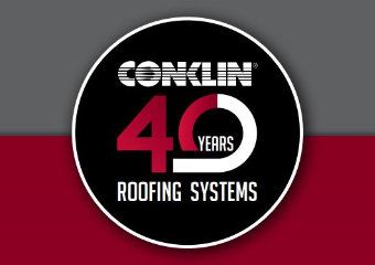 Red Hummer SUV in front of a building with a damaged roof under a cloudy sky.