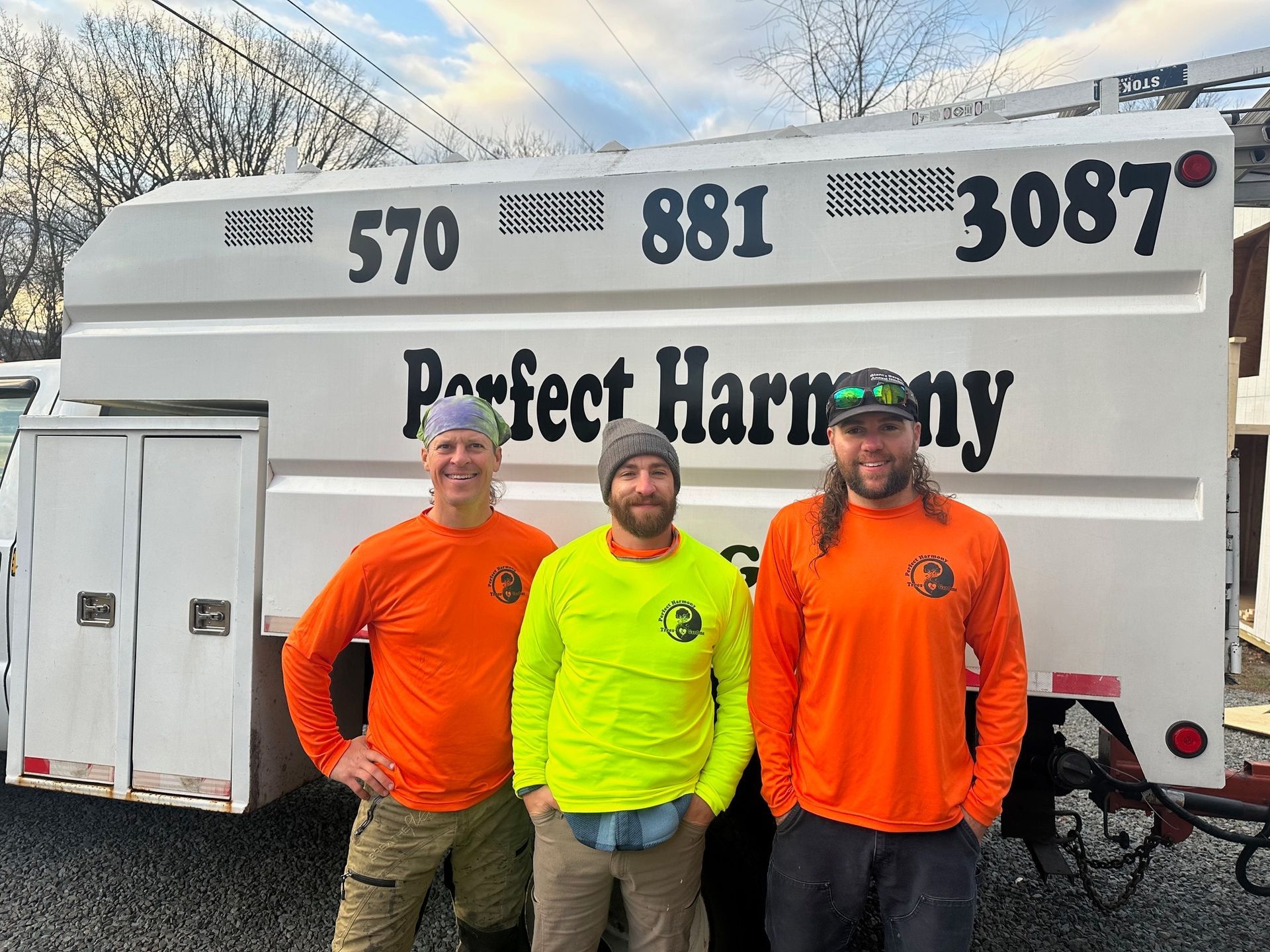 Three men are standing in front of a perfect harmony truck.