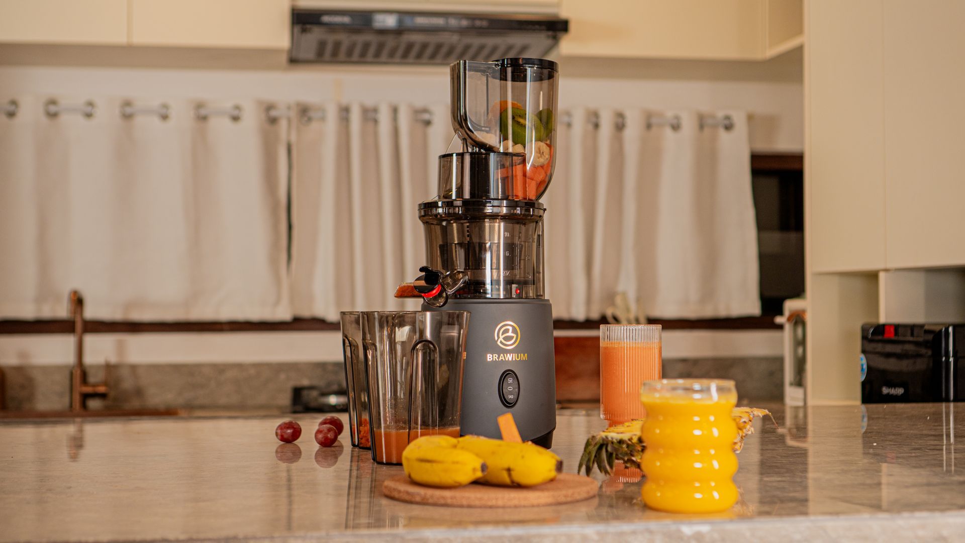 Pembuat jus berwarna abu-abu gelap dengan bagian atas terbuka, mengekstrak jus.