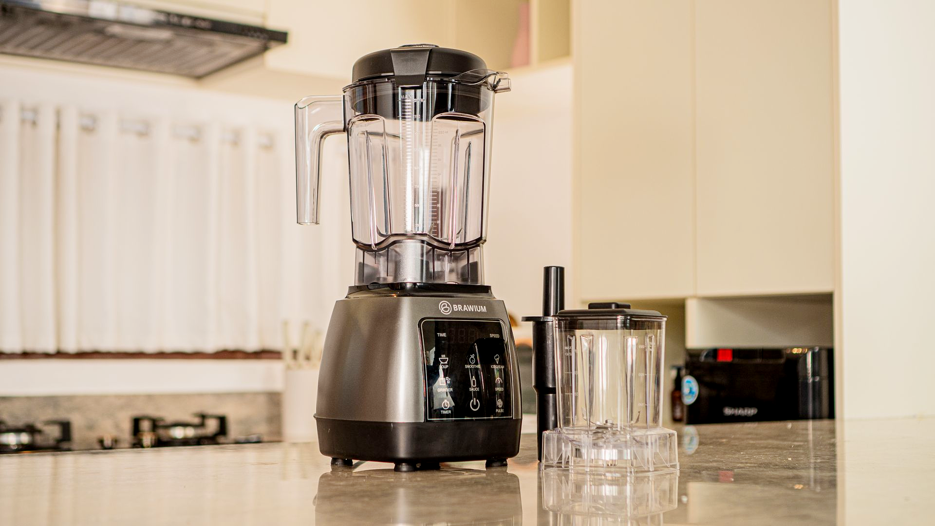 Dua wadah blender plastik bening, satu besar dengan pegangan, lainnya lebih kecil, keduanya dengan tutup hitam.