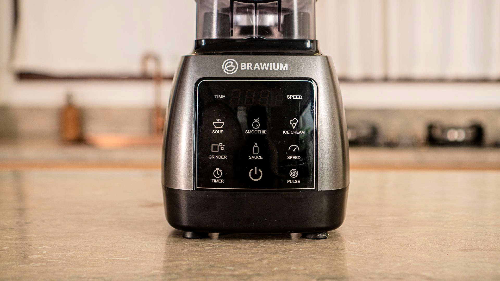 Blender abu-abu dengan layar digital dan tombol prasetel pada permukaan putih.