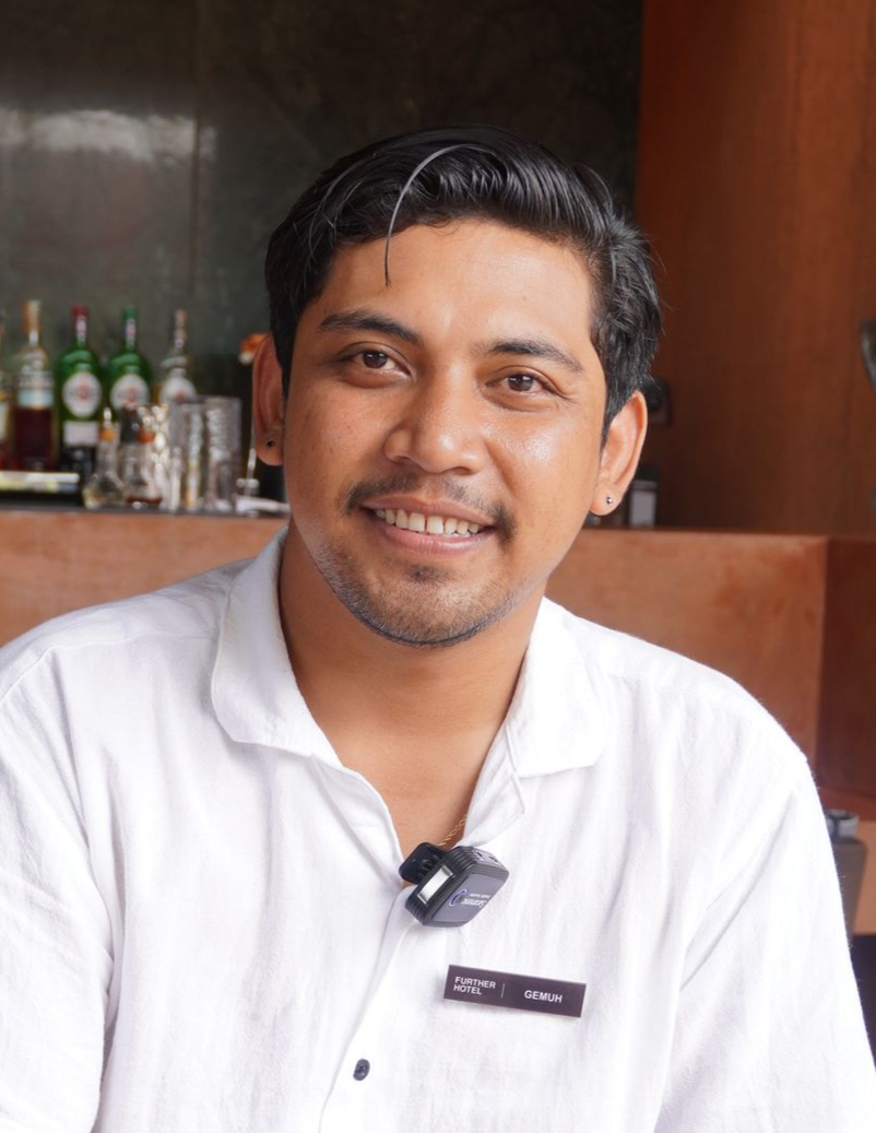 Wanita berambut pirang tersenyum sambil memegang blender di kafe.