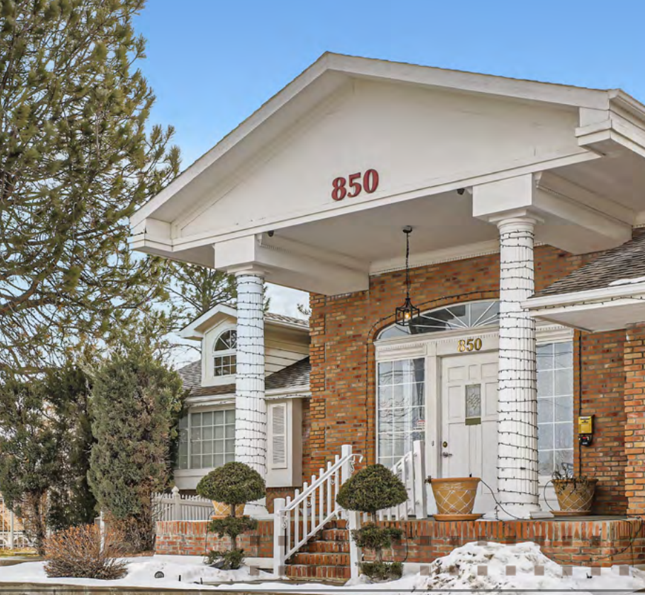 Brick house with white pillars and entry, address 850. Snow on the ground.