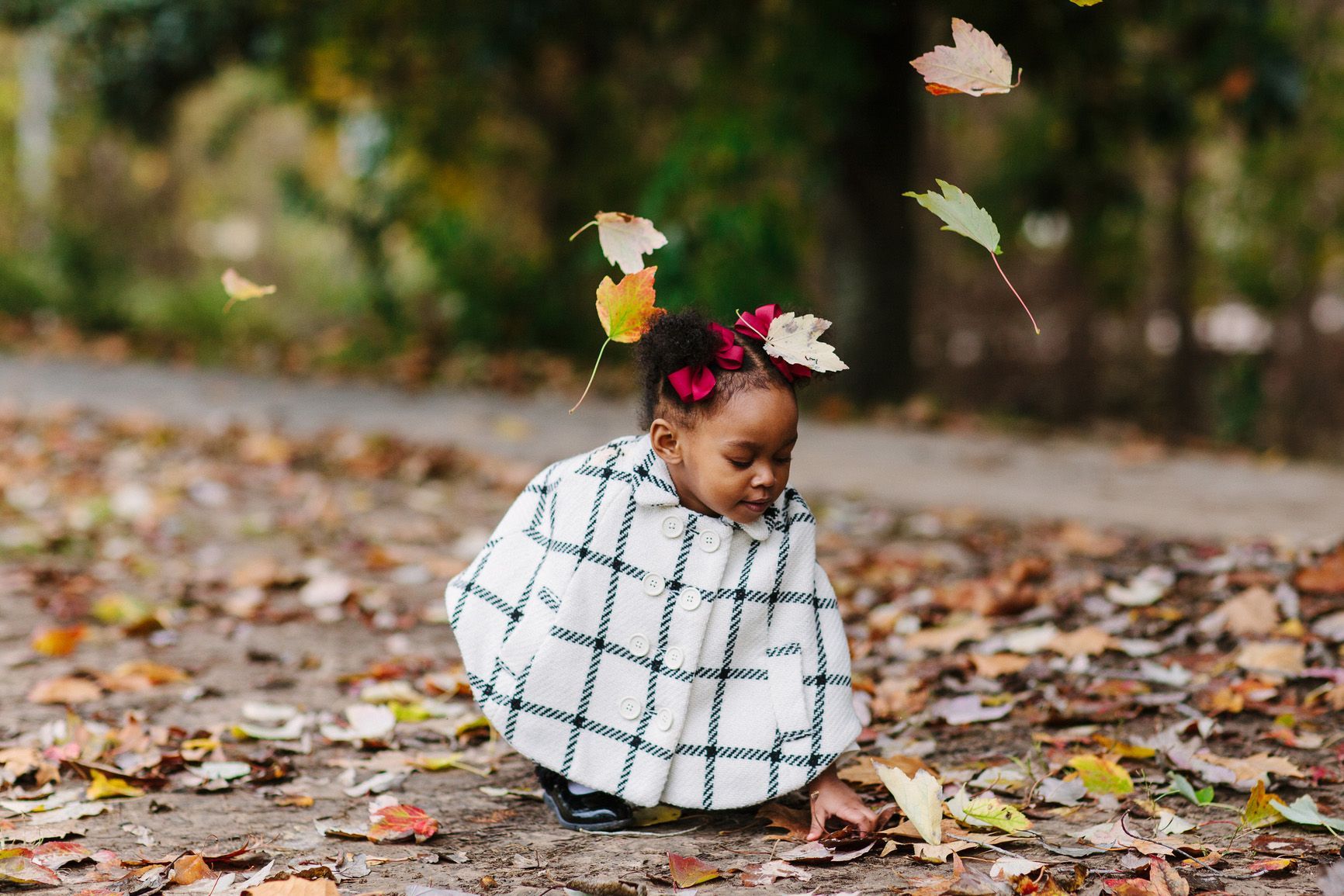 Three children sit on the edge of a pool, feet in the water. A boy sits on a pink seahorse float. Wooden fence in the background.