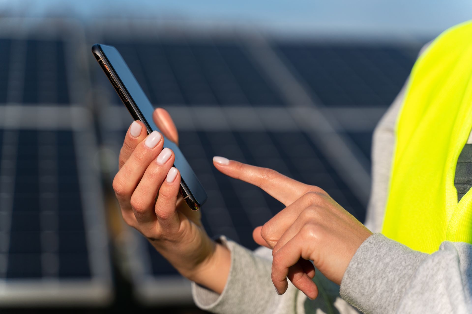 A woman is using a cell phone in front of solar panels.