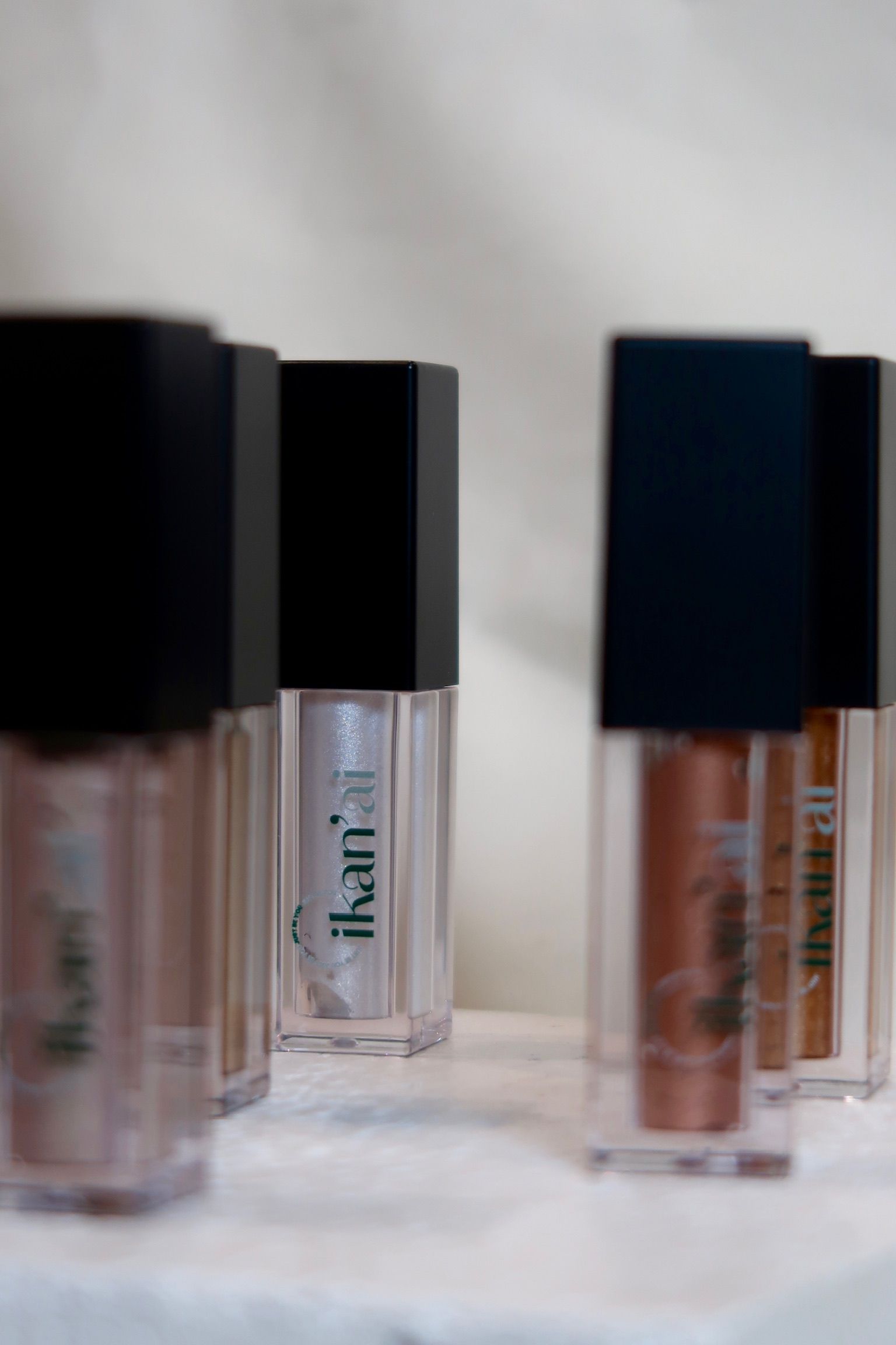 Close-up of several makeup tubes with black lids. The tubes contain shimmery pink and bronze shades — Ikan'ai In Bowral, NSW