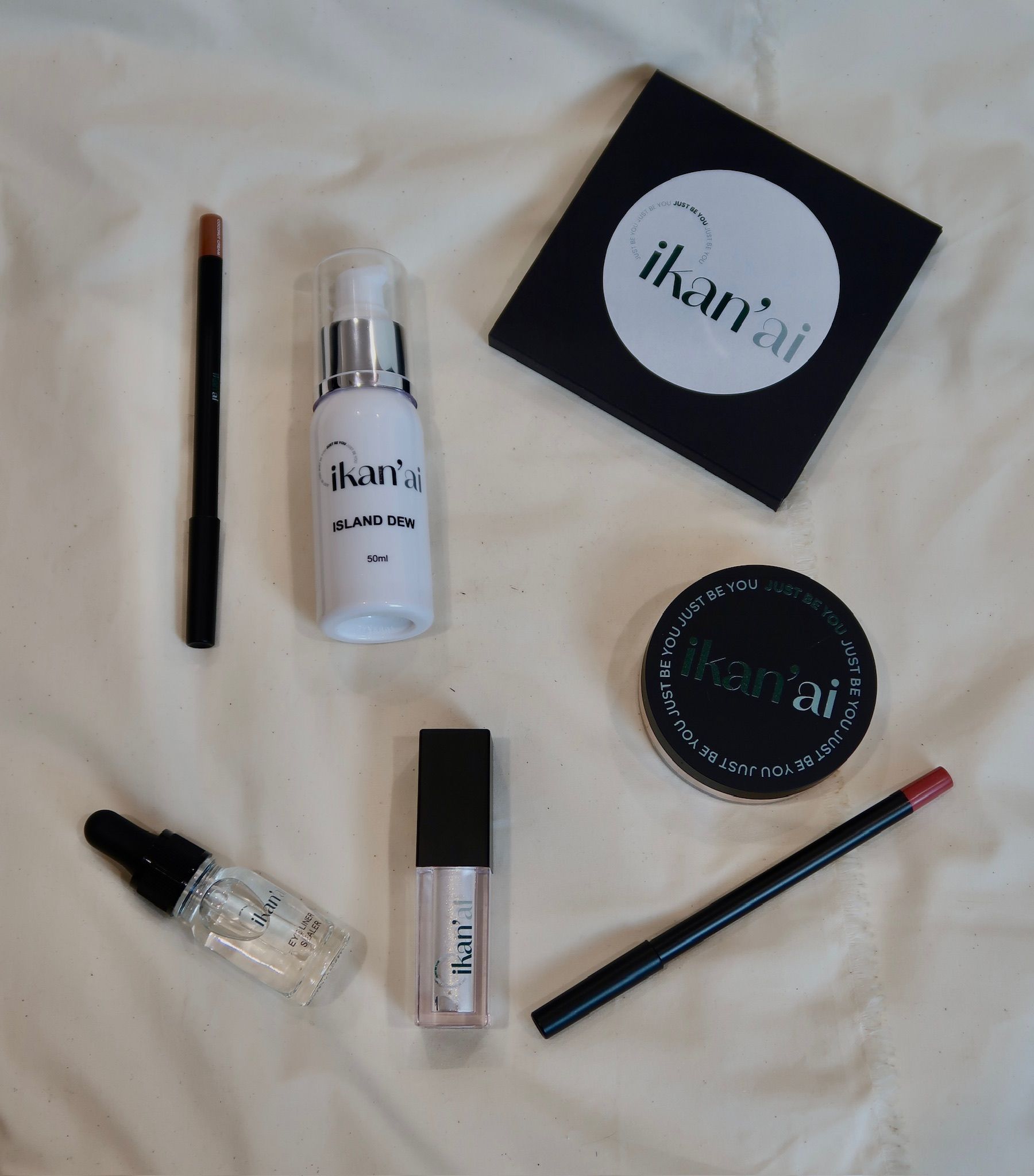 Makeup products arranged on a white surface, including lip liner, lip gloss, and eyeshadow palette — Ikan'ai In Bowral, NSW