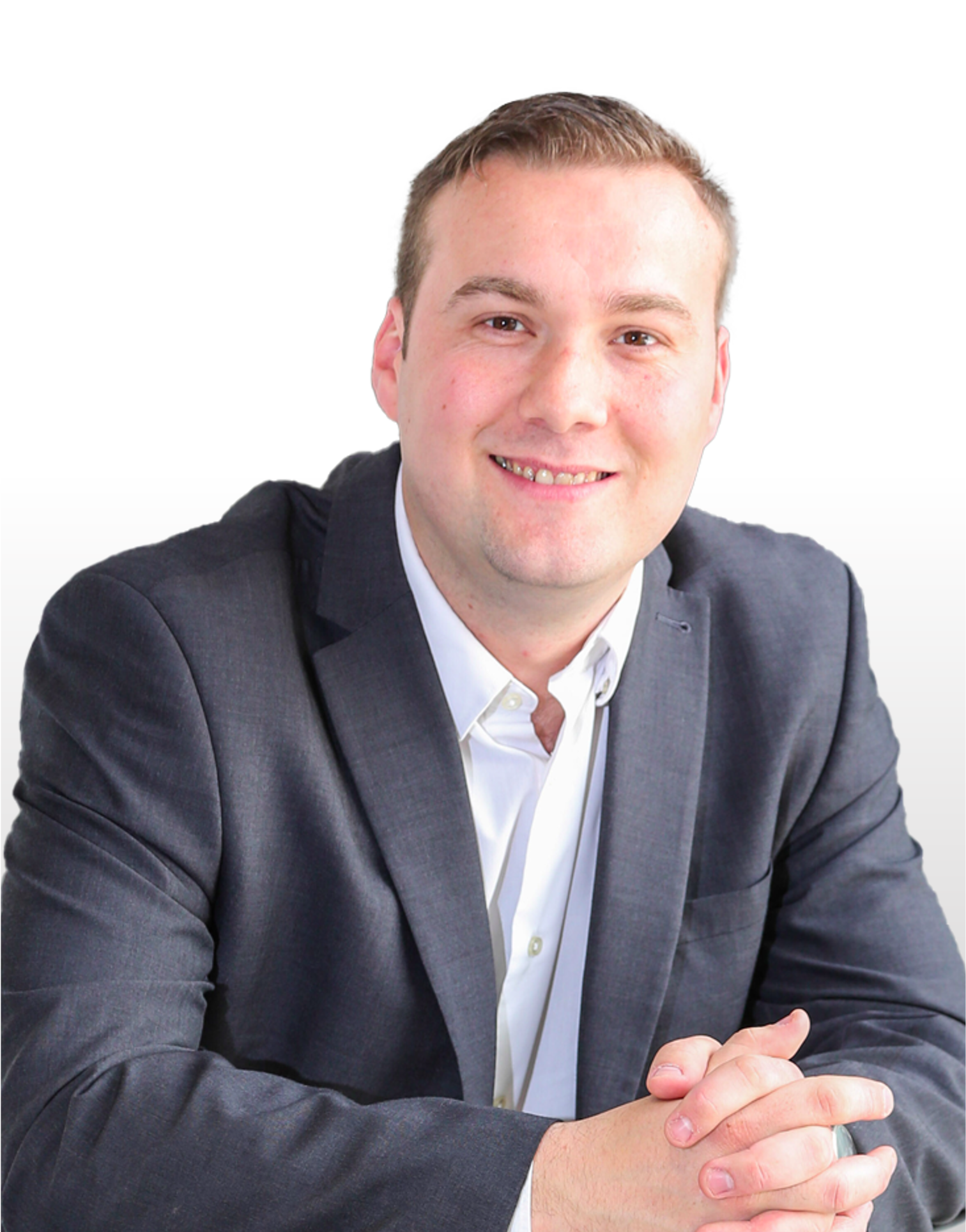 A man in a suit and white shirt is smiling with his hands folded