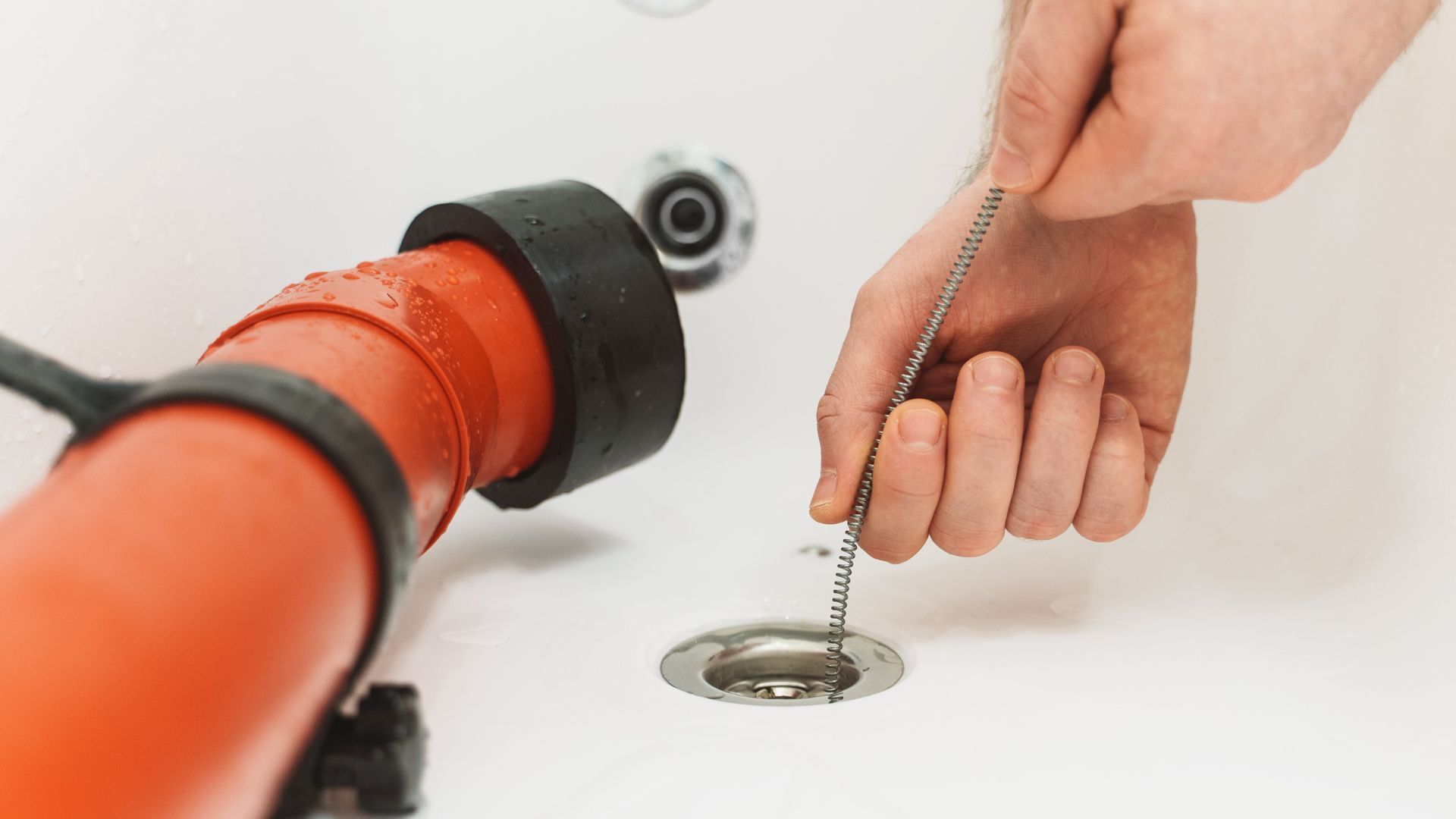 A person is using a drain cleaner to clean a drain in a bathroom.