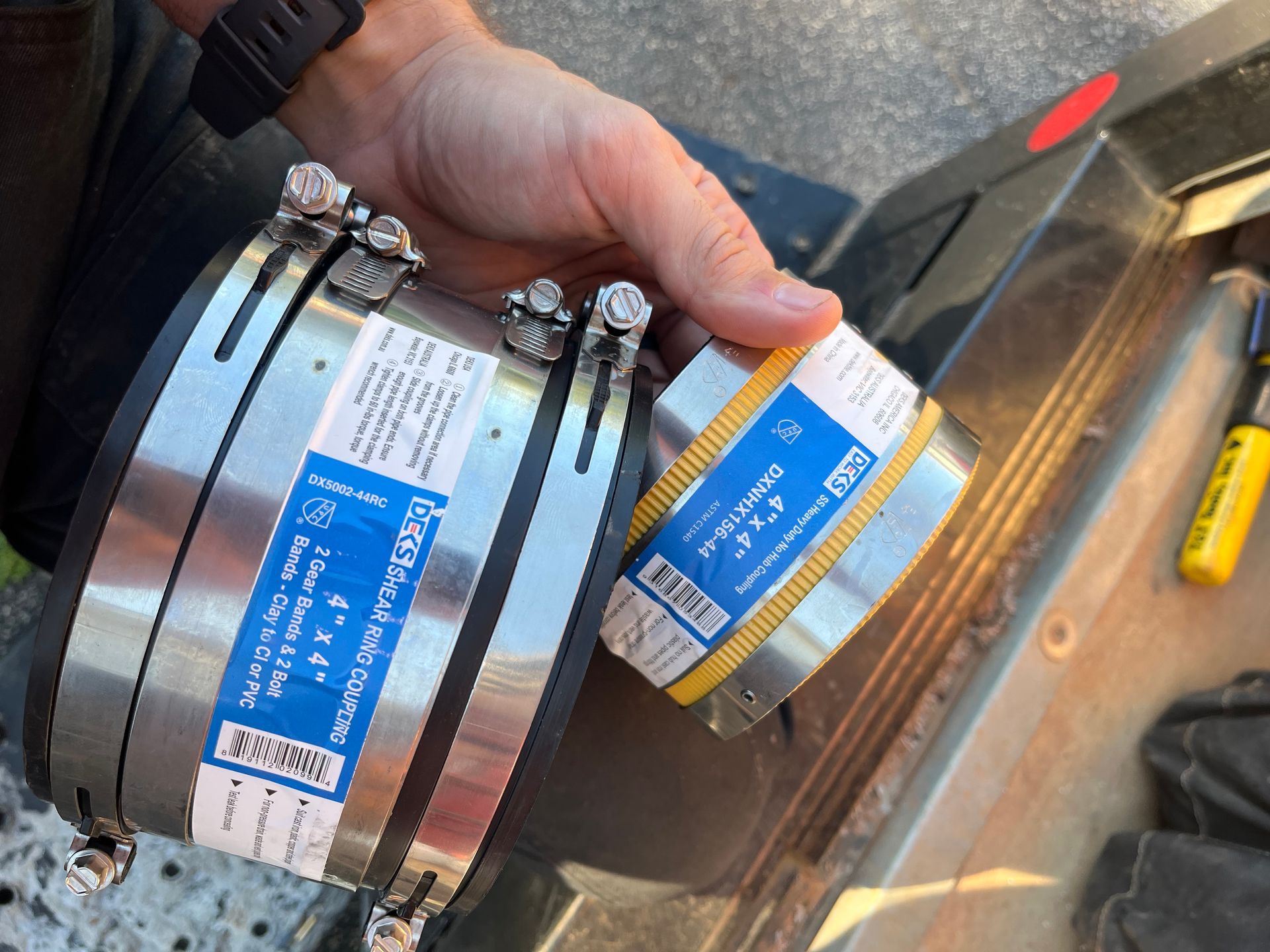 A person is holding a pair of stainless steel hose clamps