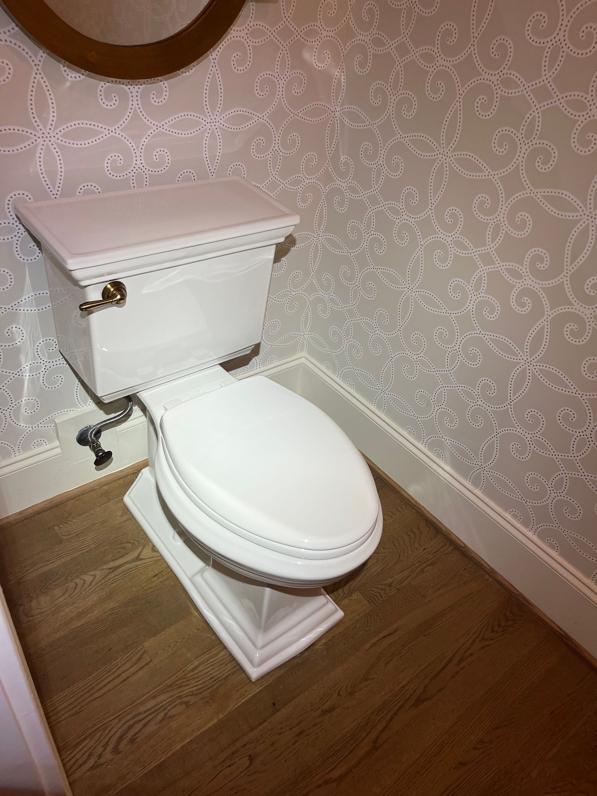 A white toilet in a bathroom next to a mirror