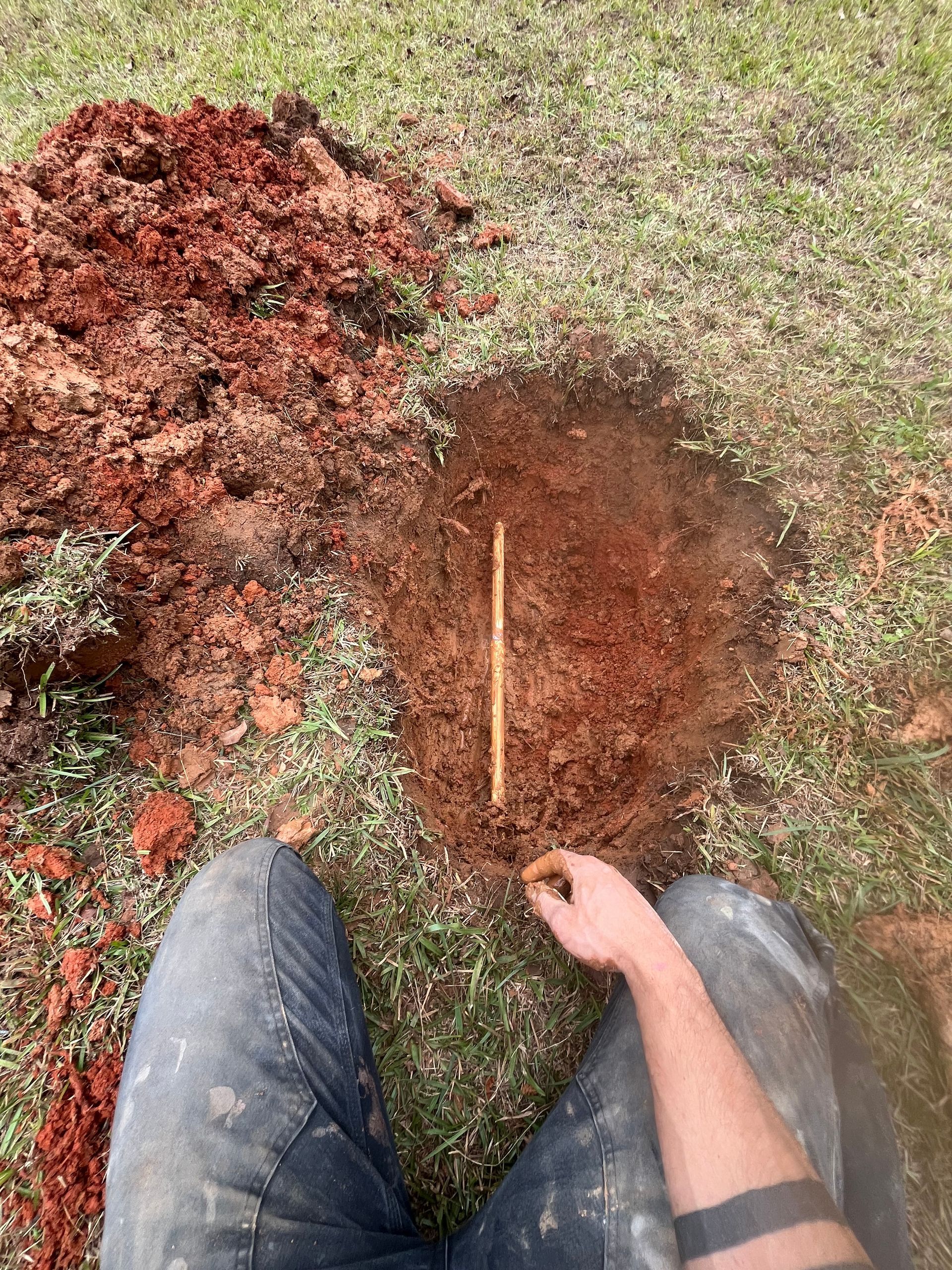 A person is measuring a hole in the ground with a ruler.
