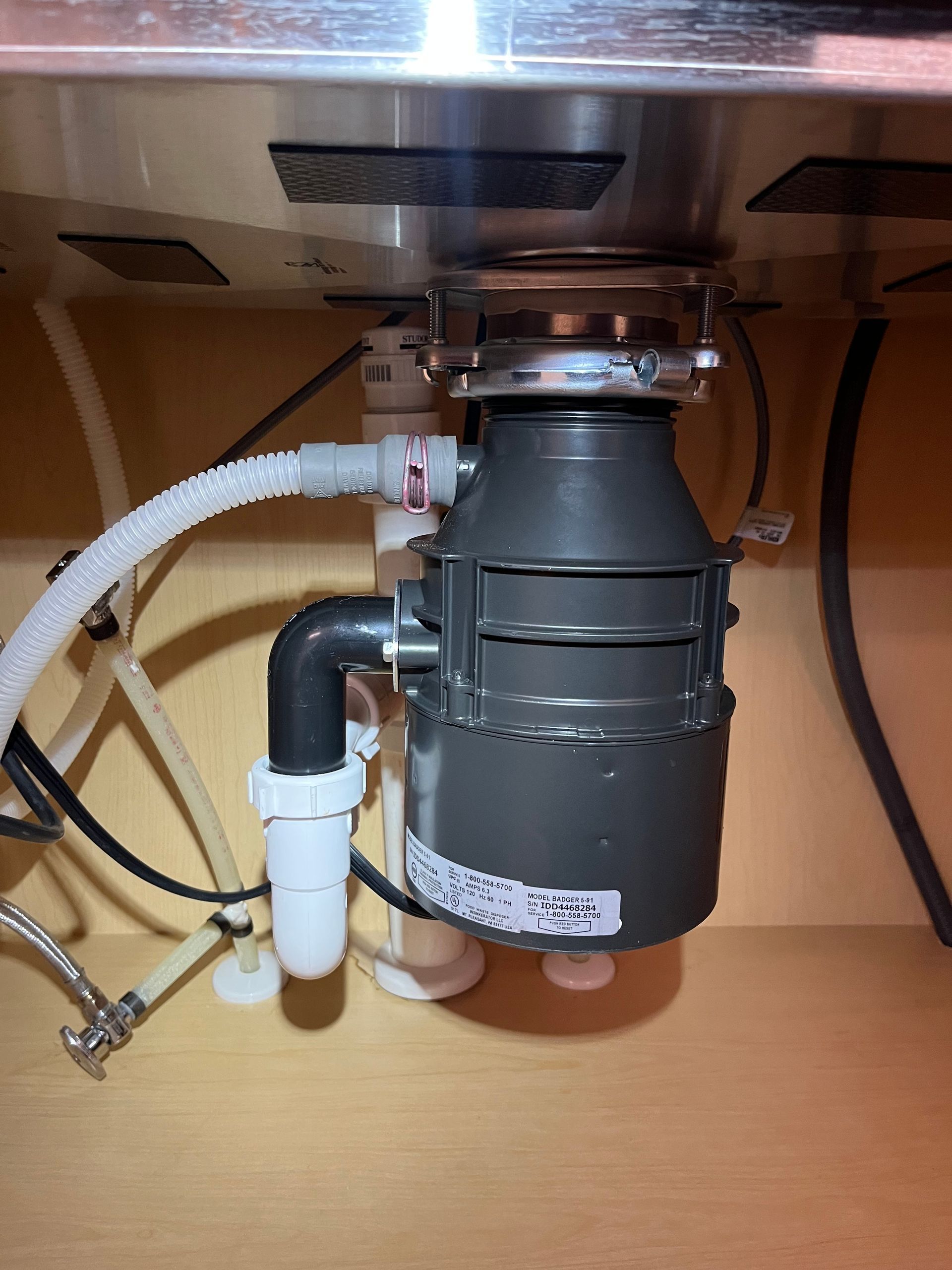 A garbage disposal is under a sink in a kitchen