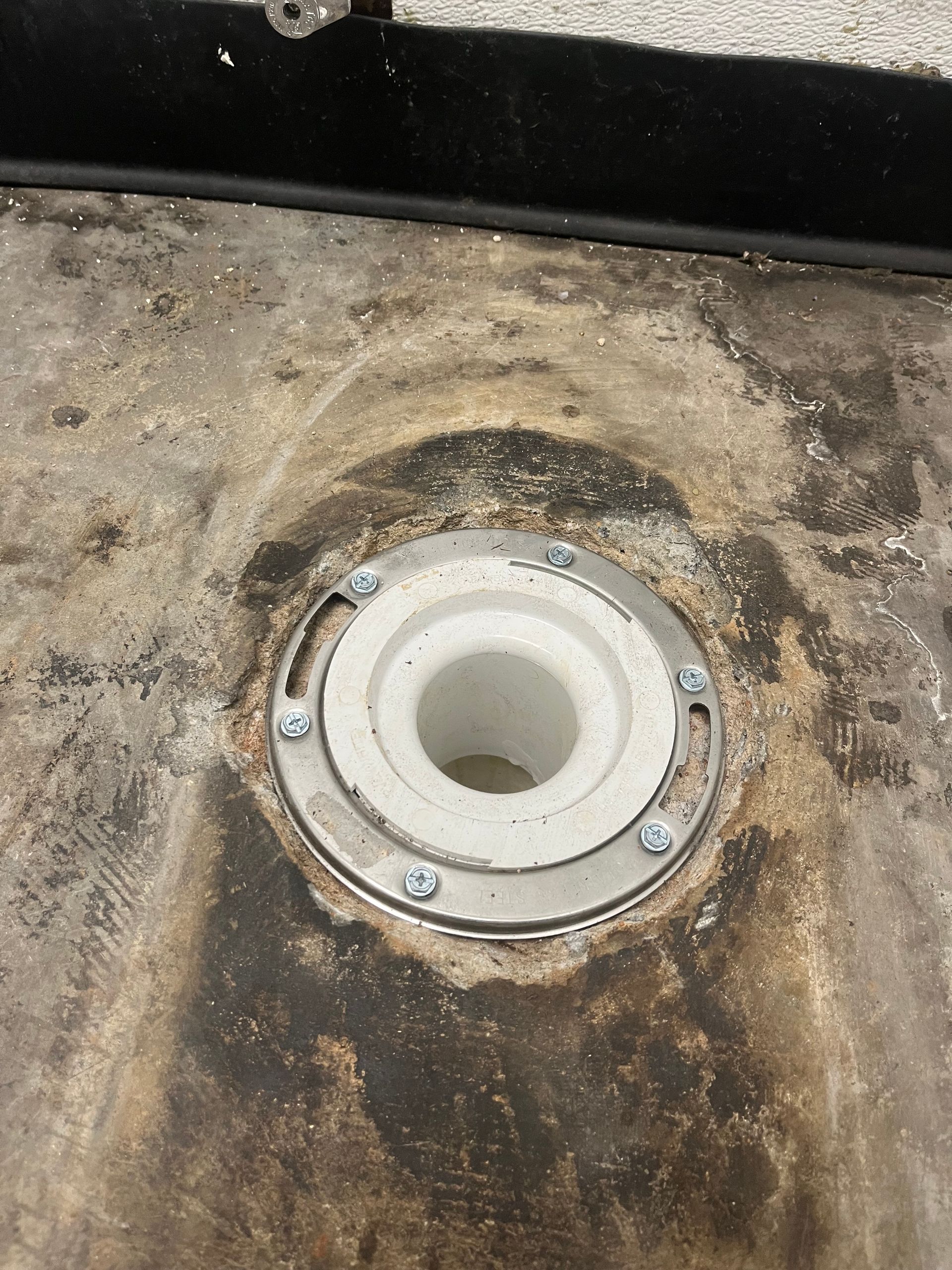 A close up of a drain hole in a concrete floor.